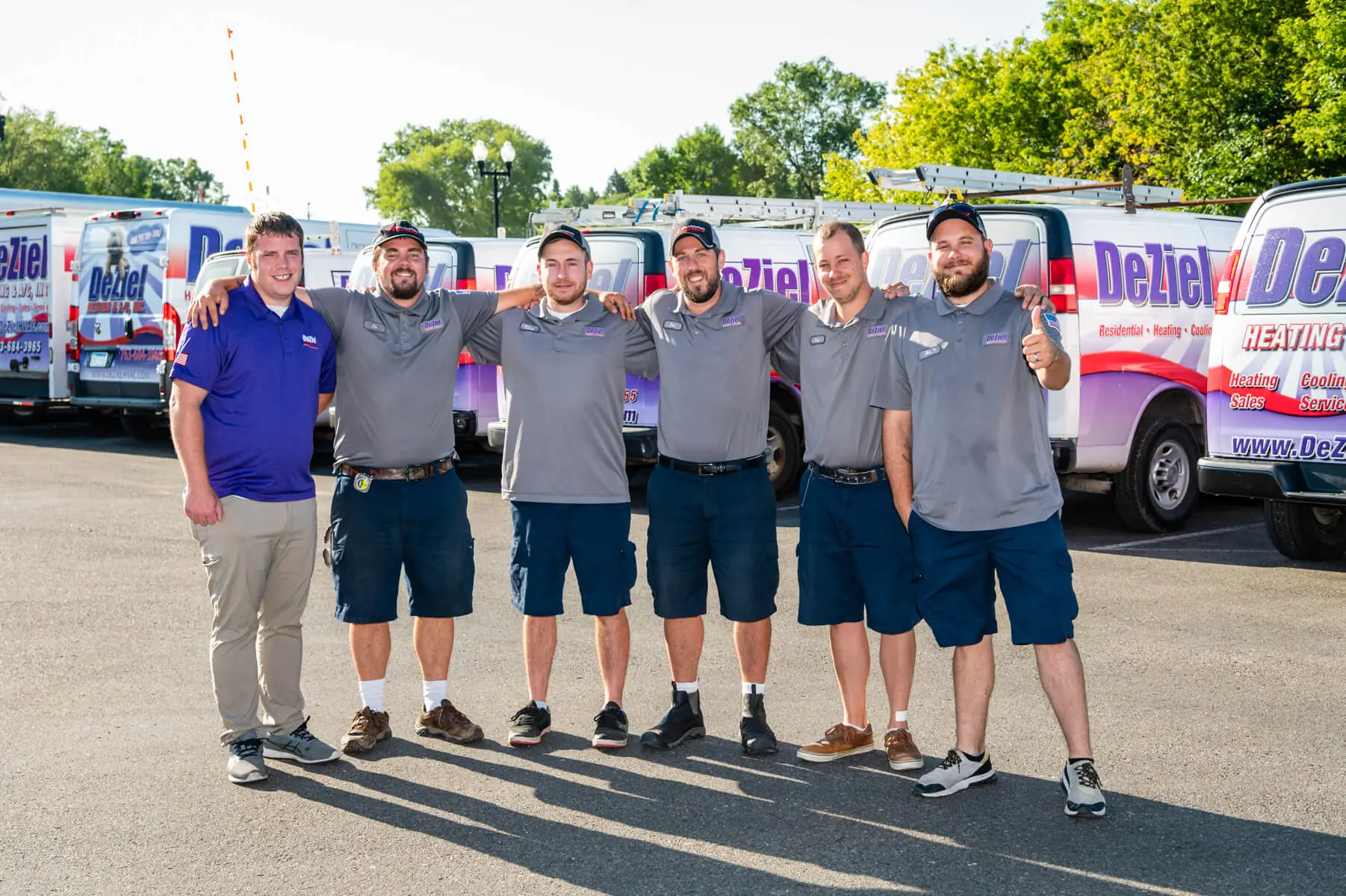 Six Men In Matching Uniforms Stand Proudly In Front Of Branded Trucks, Showcasing Their Expertise In Dehumidifier Installation. They Pose For A Group Photo In The Parking Lot, Ready To Meet Any Whole-Home Dehumidifier Needs With Professionalism And Cost-Effective Solutions.